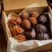 Open gift box filled with assorted chocolate truffles, caramel clusters, and molded chocolates.