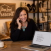 Shop owner on the phone at a counter with a laptop open to a draft social caption