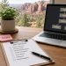 Clipboard with an SOP checklist beside a laptop flowchart on a desk overlooking red-rock landscape