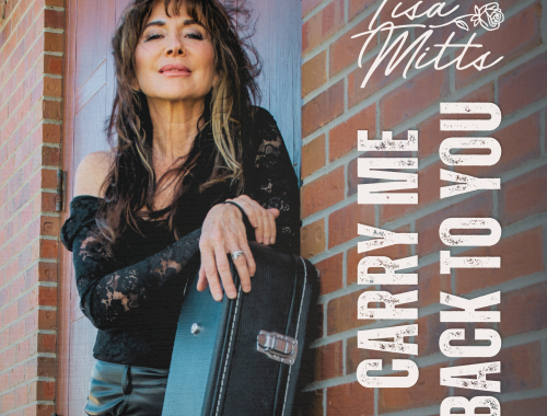 Lisa Mitts with long dark hair in black lace top leaning on red brick wall holding black guitar case for Carry Me Back To You cover
