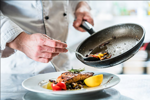 A cook prepares a plated meal in the adult day center kitchen.